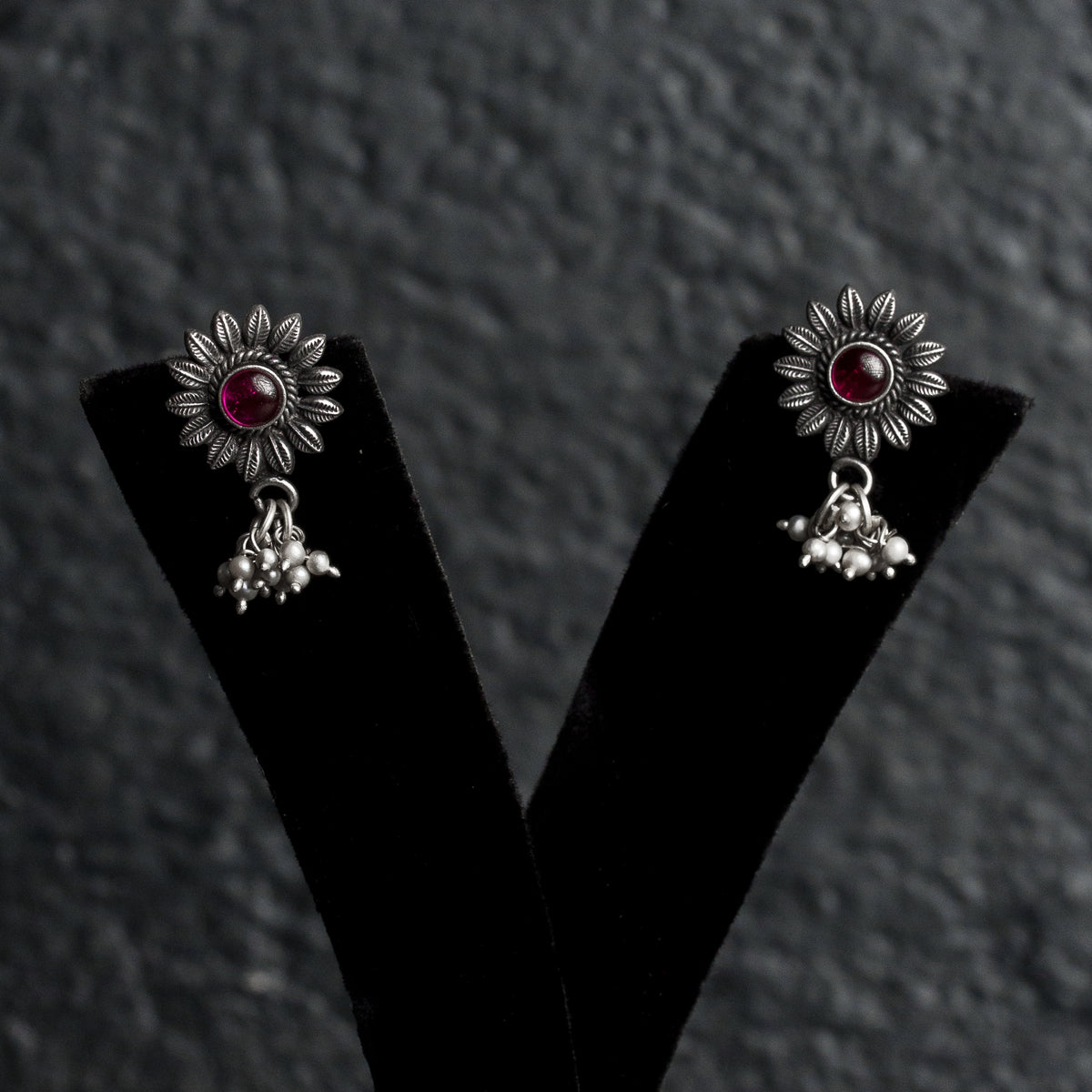 Elira Studs earrings with a sunflower-like top and a small red gemstone in the centre.
