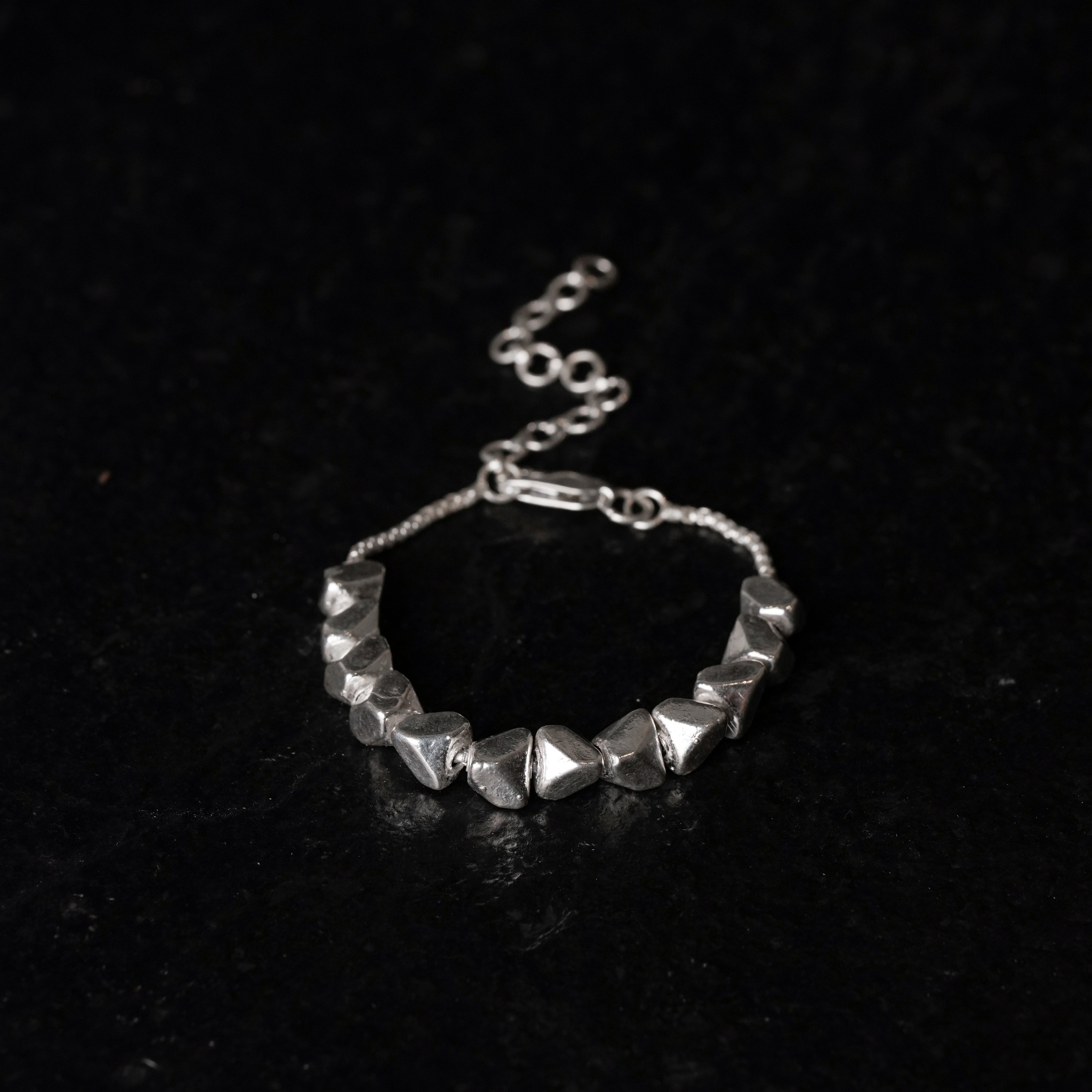 Silver beaded bracelet on a dark textured surface